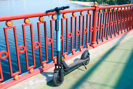 Electric scooter on the pedestrian bridge. Electric scooter rental for walking. The river is in the background.の写真素材