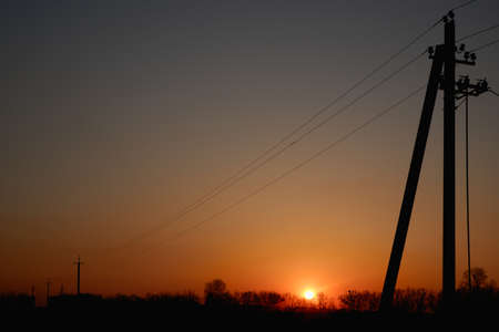 High voltage electric pylon and electrical wire with sunset sky. Electricity poles. Power and energy...