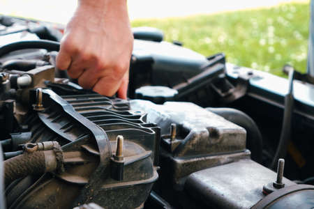 Auto mechanic working on car engine in mechanics garage. Repair service. Close up of car mechanic repairer technician repairs auto engineの写真素材