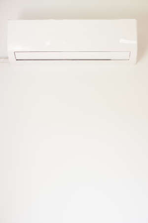 Air conditioning. Wall-mounted air conditioner unit against the background of a white wall. Vertical...