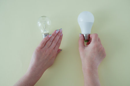 Female hands choose an LED bulb instead of an incandescent bulb. Energy saving. Concept.の写真素材