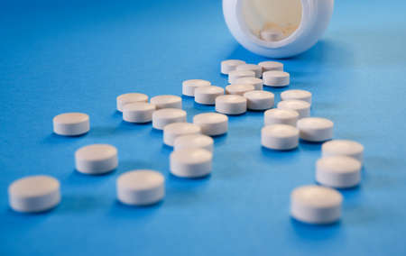 Medicine and healthcare concept. Capsules, tablets scattered near containers on a blue background....