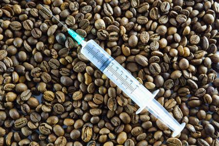 Injection syringe on the background of coffee beans. Caffeine addiction concept.の写真素材