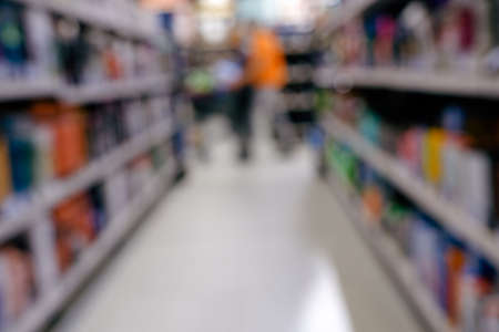 Blurred photo of a woman shopper among the shelves with goods in a supermarket.の写真素材
