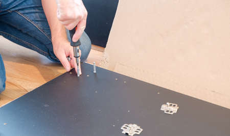Furniture assembly workflow. A man collects furniture brought from the store. Assembling the cabinet yourself.の写真素材