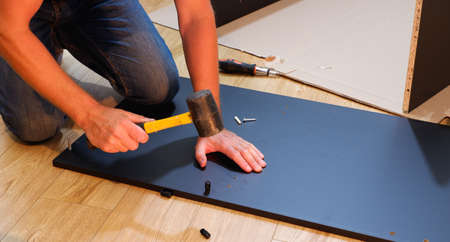 Furniture assembly workflow. A man collects furniture brought from the store. Assembling the cabinet...