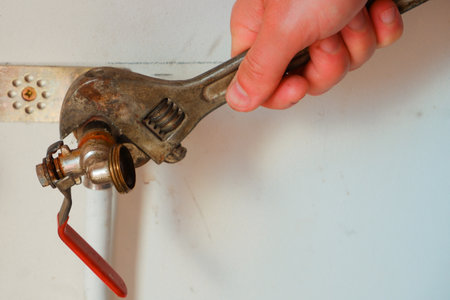 Replacement of the watering tap. The man plumber uses an adjustable wrench to turn the watering tap.の写真素材
