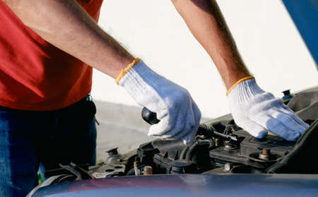An auto mechanic changes the battery in a car. An auto electrician connects the terminal to a new battery. Close-up viewの写真素材