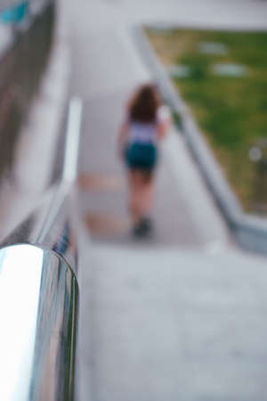 Blurred silhouette of a teenage girl in summer light clothes on the steps with a metal railing.の写真素材