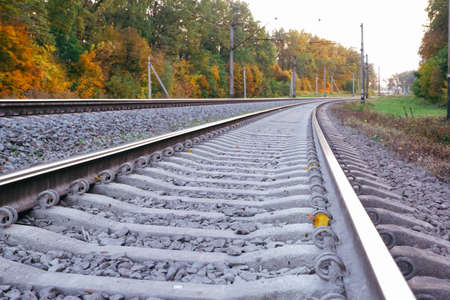 Photo of the railway. Steel rails, concrete sleepers, gravel filling. Autumn urban landscape.