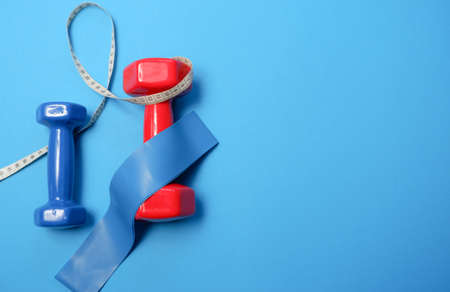 fitness sport concept. Red dumbbells and measuring tape on blue backgroundの写真素材