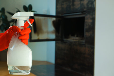 Cleaning the fireplace. Spray. A woman's hand in a red rubber glove holds a bottle of fireplace cleaner.の写真素材