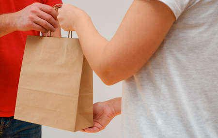Delivery of purchases in paper packaging. The courier hands the ecological shopping bags to the girl. Shopping ecological style concept.の写真素材