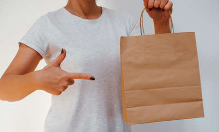 Ecological packaging. The girl holds paper bags in her hands. Happy cute unrecognizable woman came home from shopping with eco-friendly recycled paper bags.の写真素材