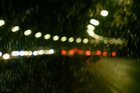 Driving a car at night in the rain. Poor visibility on the road. Blurred photo of a night road raindrops on glassの写真素材