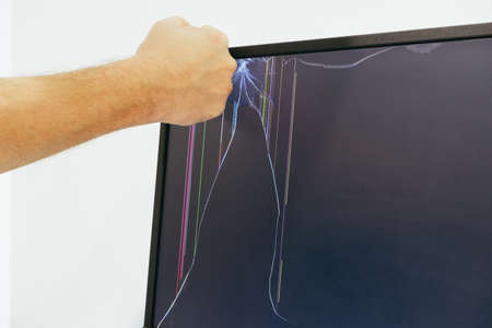 Male hand breaks the monitor screen. Broken LCD monitor. Punching the monitor.