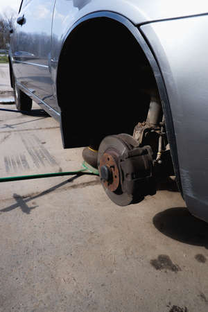 Automobile fix. Car with removed wheels on pneumatic jacks. View of the brake discs hub.の写真素材
