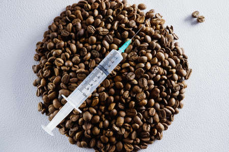 Injection syringe on the background of coffee beans. Caffeine addiction concept.の写真素材