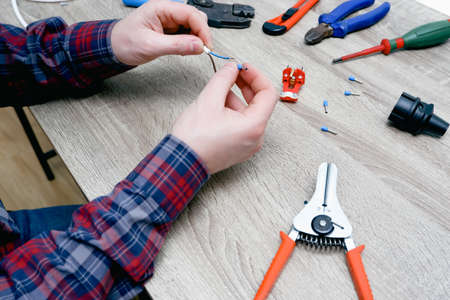 A male electrician changes the plug on an electric wire. Working with electrical tools. Stripper,...