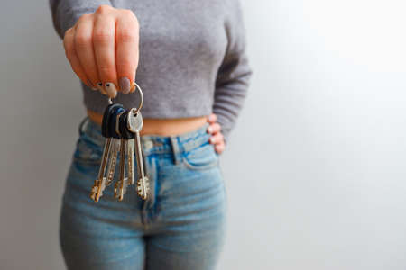 An attractive woman in jeans and a top holds out a bunch of keys in her hand. People lifestyle...