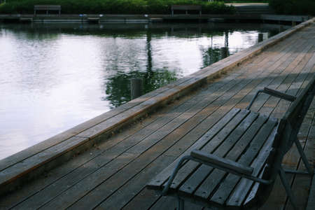 Wooden bench on the shore of the lake. Wooden promenade near the lake in the city park. European...
