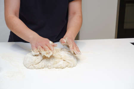 DIY home cooking concept. A young woman works with yeast dough in a modern kitchen. A young woman is...