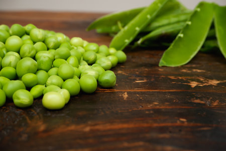 Fresh peeled green pease on a brown wooden table with copy space. Fresh pods of green peas horizontal composition isolated on a old rustic wooden surface, soft focusの写真素材