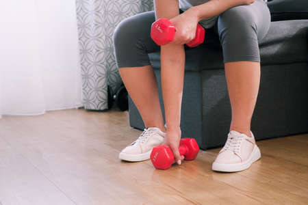 sportswoman practicing aerobics with dumbbells. woman lifting weights and working out at home....