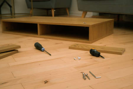 Assembly of furniture, the different parts and pieces of furniture arranged on the wooden floor. DIY...
