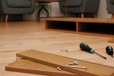 Assembly of furniture, the different parts and pieces of furniture arranged on the wooden floor. DIY...