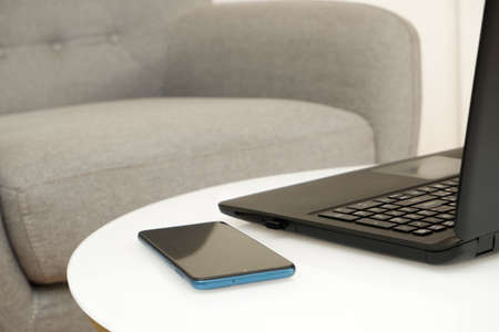 Remote work from home. Laptop on a white coffee table near the armchair. The workplace of...