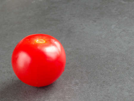 Fresh organic tomato on gray background. One ripe red tomato on a dark backgroundの写真素材