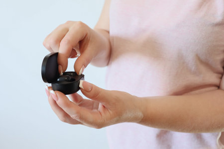 Close up of woman is holding the black true wireless earbuds case in hand. Close-up hands of...