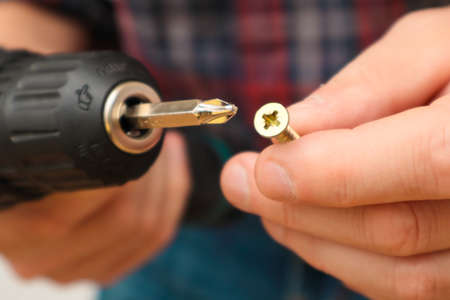 Handworker working with an electric screwdriver. A man using the drill in the home