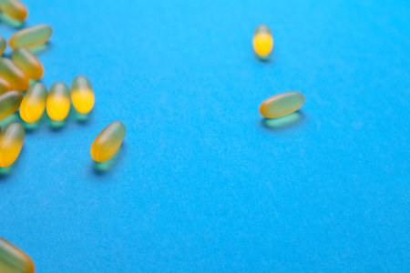 Fish oil omega 3 gel capsules on blue background with copy space. Healthcare, vitamins, supplements daily intake concept. Fish oil, omega3, vitamin D, vitamin Eの写真素材
