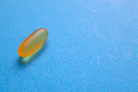 Fish oil omega 3 gel capsules on blue background with copy space. Healthcare, vitamins, supplements daily intake concept. Fish oil, omega3, vitamin D, vitamin Eの写真素材