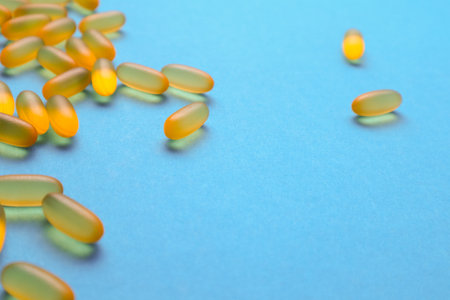 Fish oil omega 3 gel capsules on blue background with copy space. Healthcare, vitamins, supplements daily intake concept. Fish oil, omega3, vitamin D, vitamin Eの写真素材