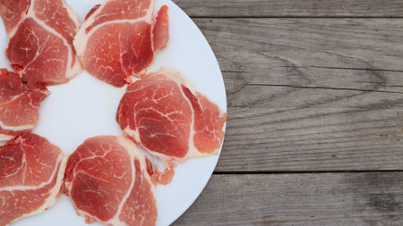Raw Pork Slice in White Round Plate on old Wooden Table.の写真素材