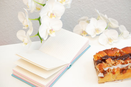 Flat lay white note pad on white table with sweet peanut pie and magnolia flowersの写真素材