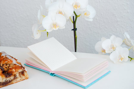 Flat lay white note pad on white table with sweet peanut pie and magnolia flowers