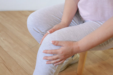 Knee pain. Woman suffering from pain in knee, close up. Middle age woman holding painful part of...