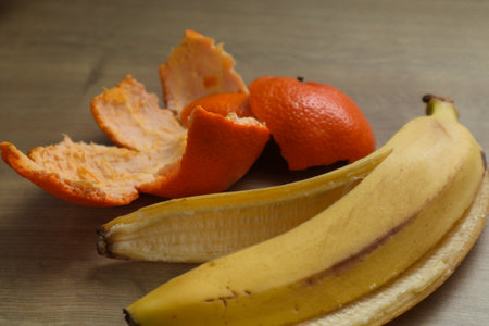 Banana and tangerine peel on a wooden background, closeup. slippery banana skin. food zero waste conceptの写真素材