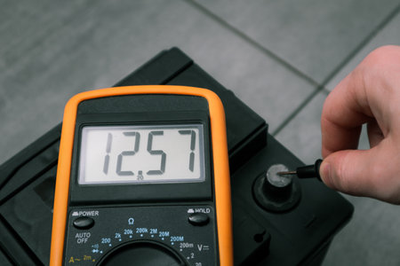 Check and charge car battery with charger. Person measures voltage. Selective focus an auto mechanic...