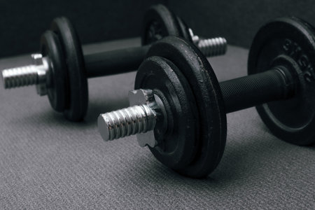 Two 10 kg dumbbells on a gray sports mat. Sports concept - gray mat, two black dumbbells. Active lifestyle sport. Workout at home or gymの写真素材