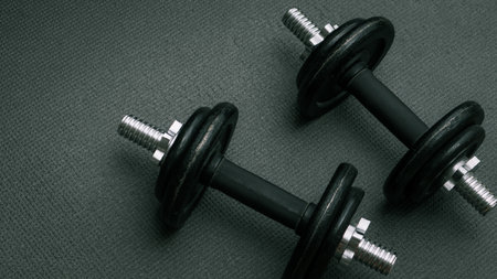 Two 10 kg dumbbells on a gray sports mat. Sports concept - gray mat, two black dumbbells. Active...