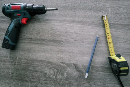 Basic construction tools set. Electric Screwdriver Pencil And Measuring Tape on wooden background.の写真素材