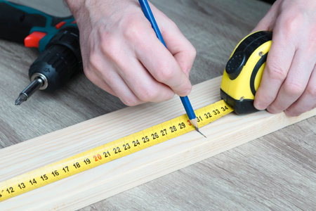 Carpenter, builder and diy for home improvement, development and repair. Making measurements with measuring tape and making marks with pen. Close up of male hands measuringの写真素材