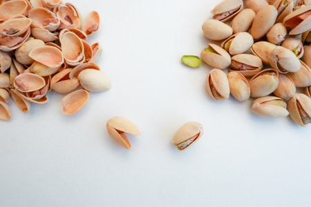 A pile of Pistachio nuts and nutshell on a white background. Pistachios background, place for text.