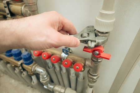 Plumber at work, plumbing repair service, assemble and install concept. Plumber's Hand Repairing Leakage With Adjustable Wrench.の写真素材