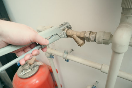 Plumber at work, plumbing repair service, assemble and install concept. Plumber's Hand Repairing Leakage With Adjustable Wrench.の写真素材